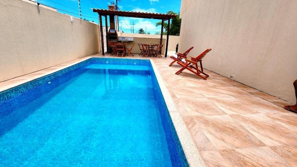 uma piscina com duas cadeiras e uma mesa em 2 suítes c/ Ar, Piscina, Churrasqueira, 500mt Mar em Santa Cruz Cabrália