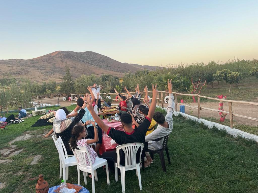 Un groupe de personnes assises dans des chaises, les mains dans l'air dans l'établissement DAR MIMONA, 