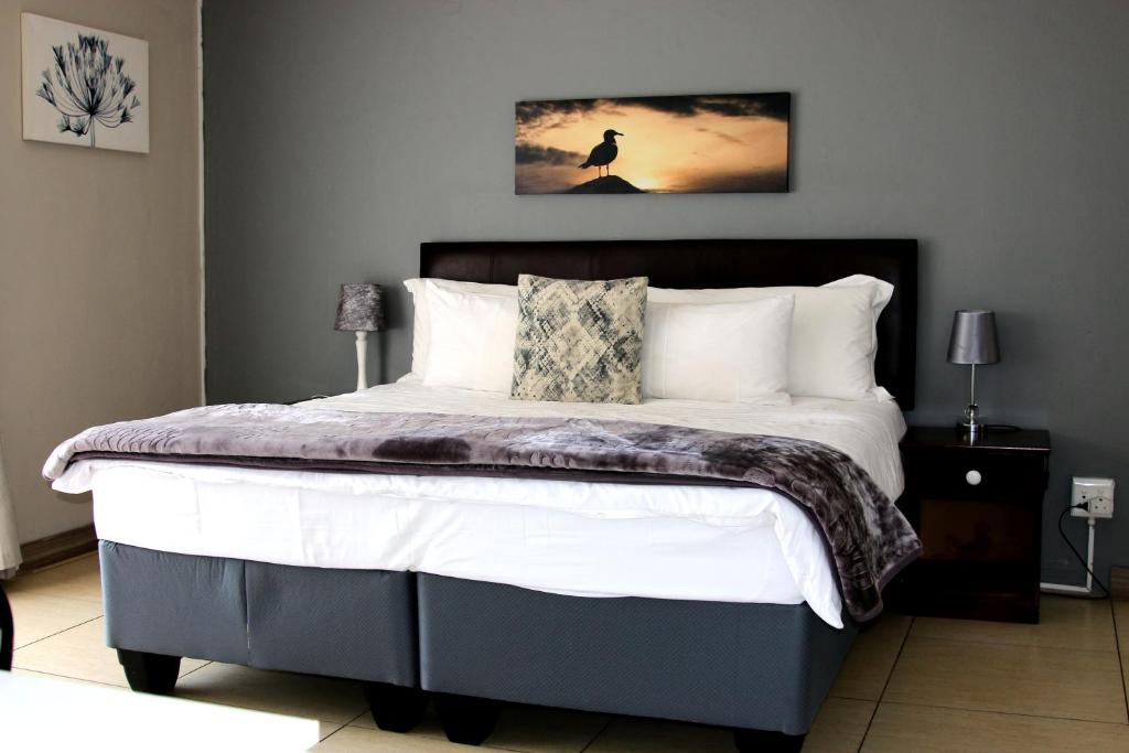 a bedroom with a large bed with white pillows at African Kingdom Guest House in Boksburg
