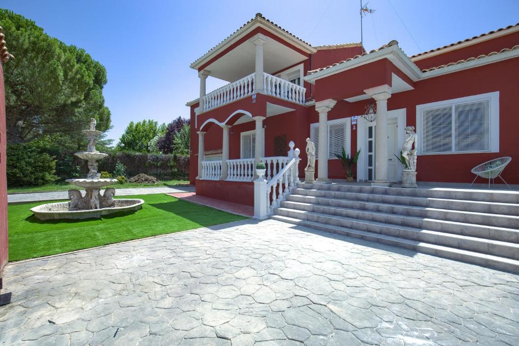 una casa roja con una fuente en el patio en Lillo Rural, en Toledo