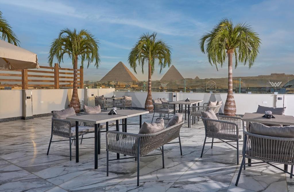 een patio met tafels en stoelen en palmbomen bij Peace Inn West Pyramids Cairo in Caïro