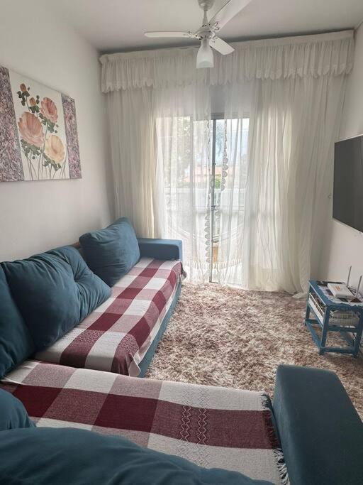 uma sala de estar com um sofá e uma janela em Apto no centro de Bertioga em Bertioga