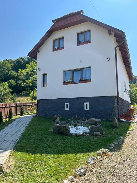 a large white house with a garden in front of it at Lenilla Guesthouse in Şiclod