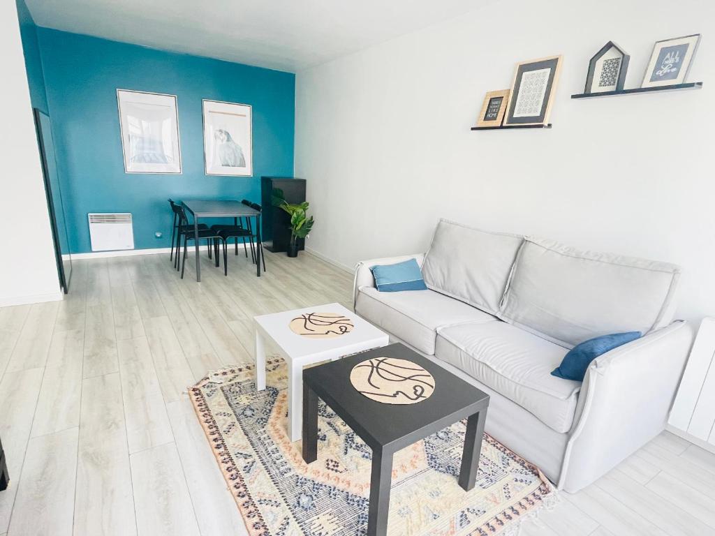 ein Wohnzimmer mit einem Sofa und einem Tisch in der Unterkunft Cosy appart proche Paris in Saint-Denis