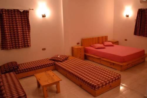 a bedroom with two beds and a bench and a table at Big Dune camp in Nuweiba