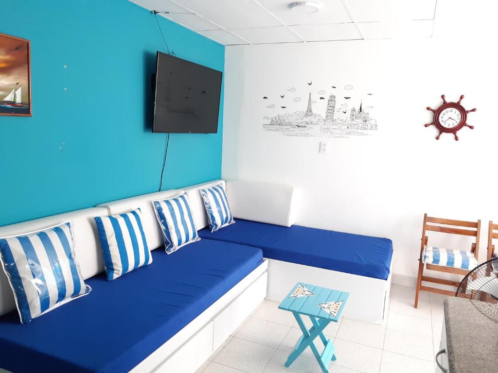 ein Wohnzimmer mit einem blauen Sofa und einem TV in der Unterkunft SUITES IN CARTAGENA QUiET LOCATION NEXT TO THE BEACH in Cartagena de Indias