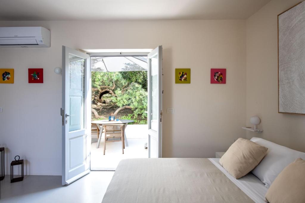 a bedroom with a bed and a door leading to a patio at Vico San Lorenzo - Camere a Salina in Malfa