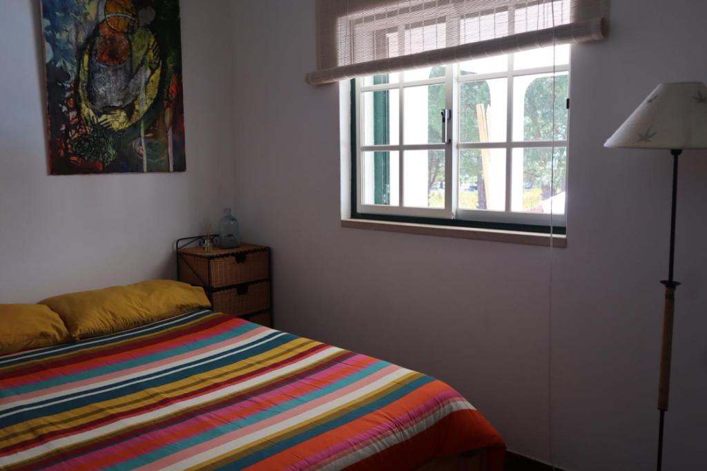 a bedroom with a colorful bed and a window at Monte Santo in Montargil