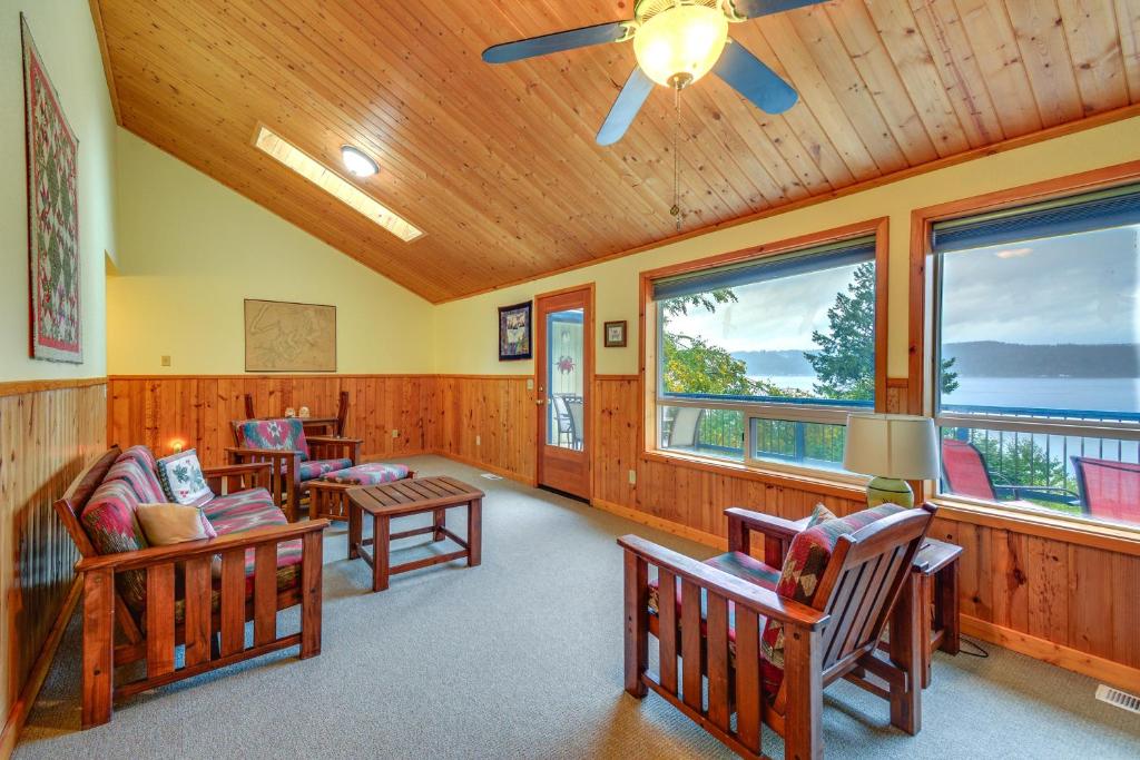 a living room with chairs and tables and windows at Tahuya Cabin Hood Canal and Olympic Mountain Views! in Tahuya