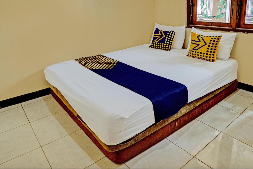 um quarto com uma cama com almofadas azuis e amarelas em OYO 93107 Homestay H Syarif Syariah – Bandar Gresik em Gresik