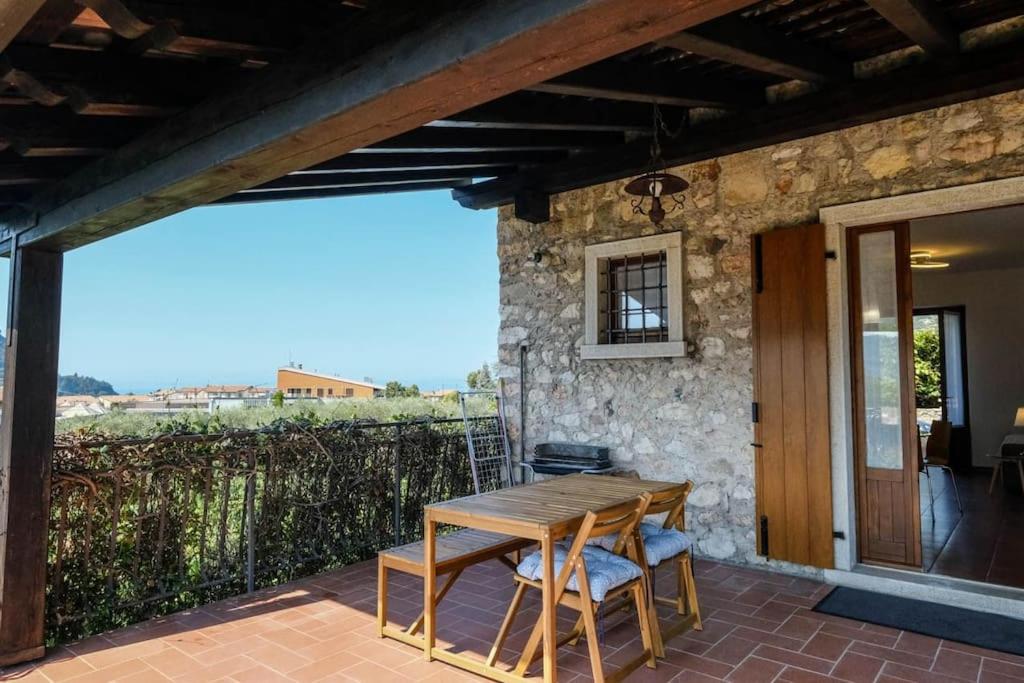 einen Holztisch und Stühle auf einer Terrasse in der Unterkunft Casa delle Ochette in Costermano sul Garda