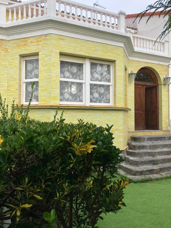 una casa amarilla con porche y puerta en El Chalet Amarillo, en Cabañas