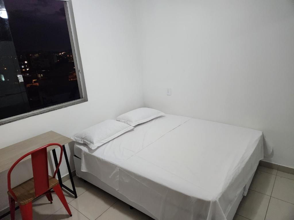 a bedroom with a bed and a chair and a window at Rooftop 402: cobertura de um quarto no centro in Sete Lagoas