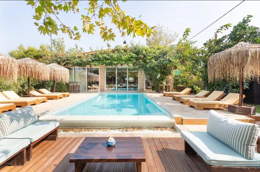 a swimming pool in a backyard with chairs and a table at Turdus Merula Retreat in Nea Makri