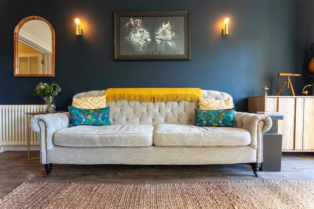 un sofá en una sala de estar con una pared azul en Georgian House Garden Apartment en Bath
