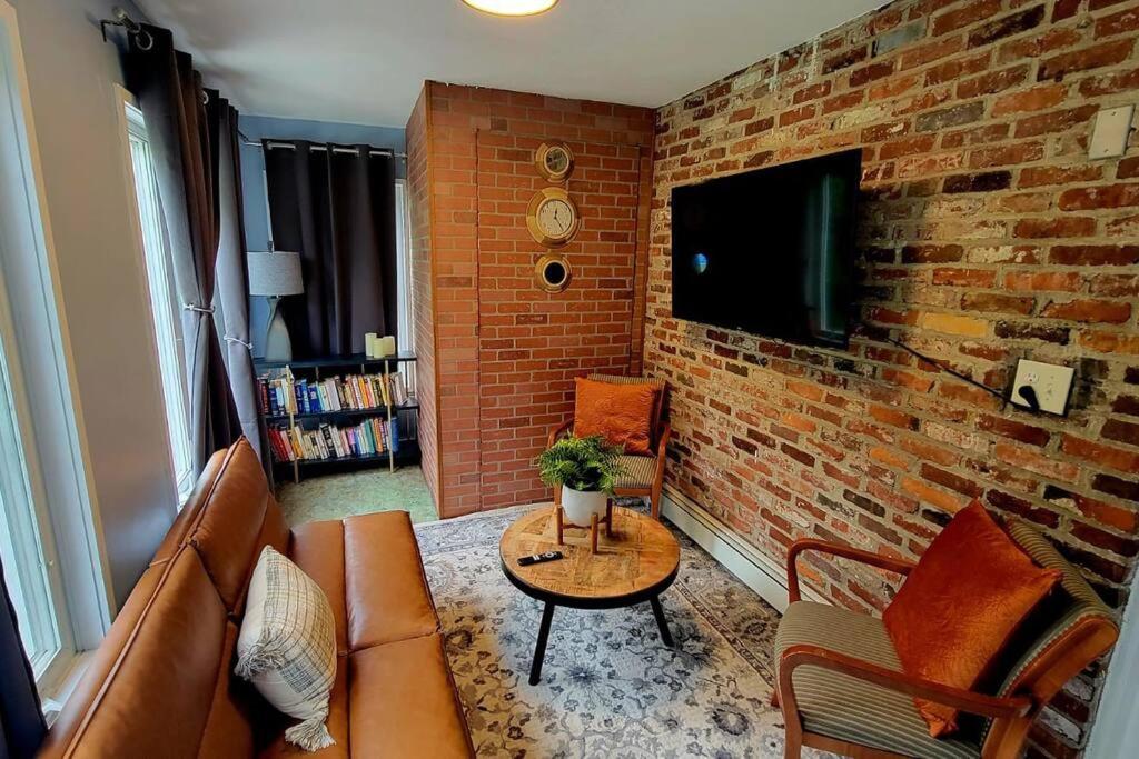 Unique & Peaceful Boston Home( Free Parking) في بوسطن: غرفة معيشة مع أريكة وجدار من الطوب