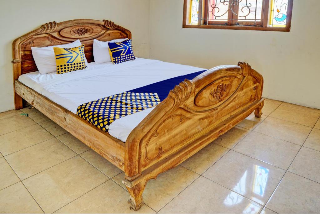 een bed met een houten frame in een kamer bij SPOT ON 93144 Homestay H. Syarif Syariah - Bandar Gresik 2 in Gresik