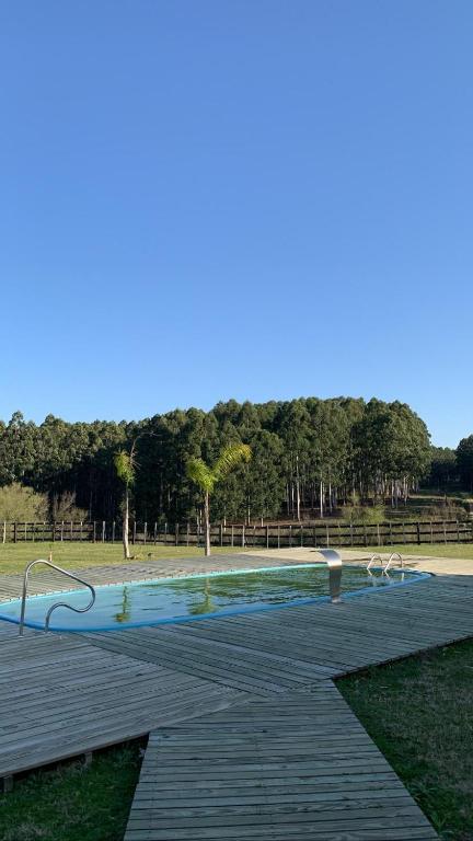una piscina en un parque con terraza de madera en Cabaña Familiar en Complejo Los Tres Rubios, en Rivera