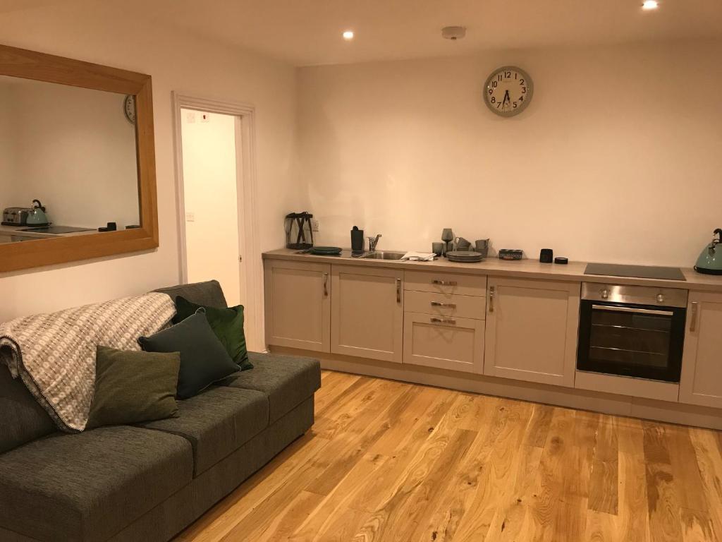 ein Wohnzimmer mit einem Sofa und einer Küche in der Unterkunft Redhill Lodge in Farnham