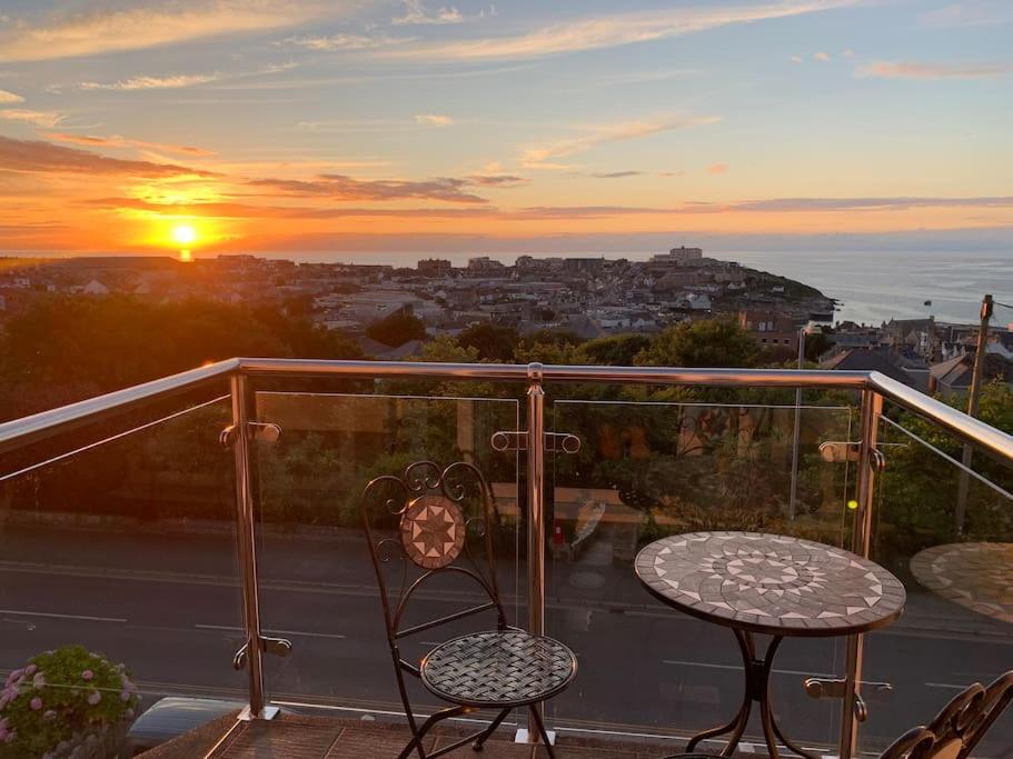 a balcony with two chairs and a table and a sunset at Newquay Sunset & Sea View Apartment in Town Centre in Newquay