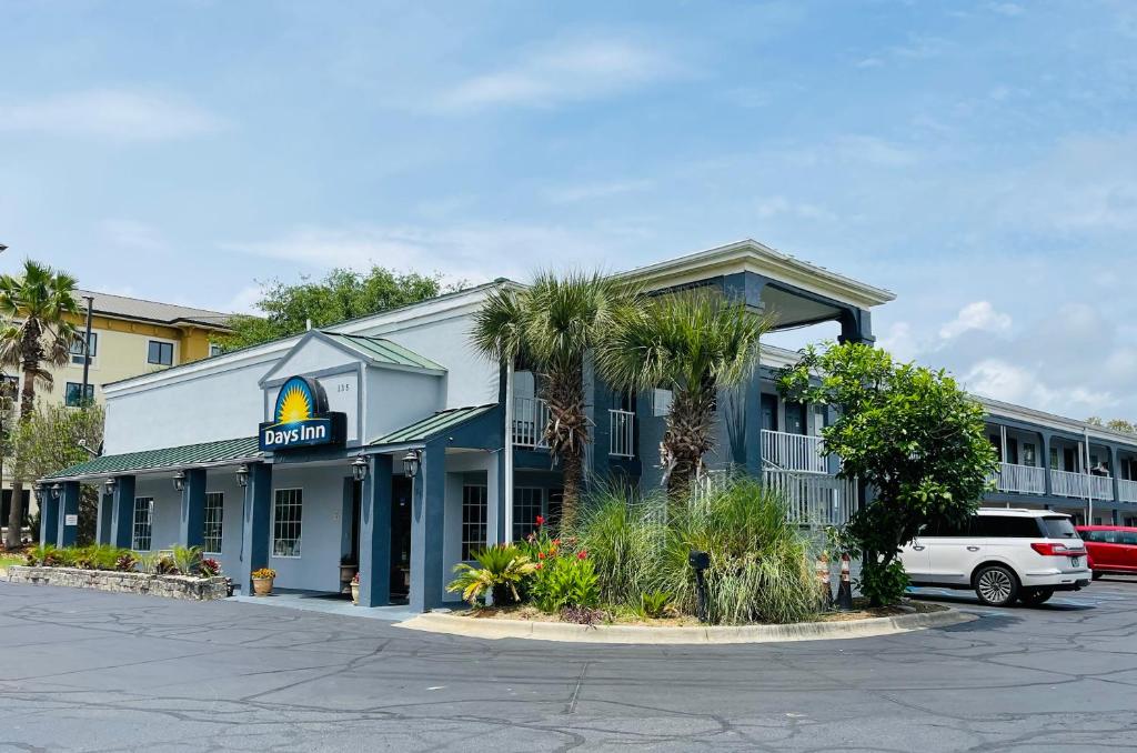 a hotel with palm trees in a parking lot at Days Inn by Wyndham Fort Walton Beach in Fort Walton Beach