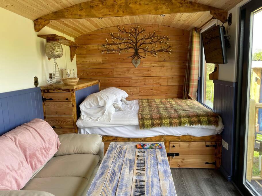 a small bedroom with a bed and a couch at Pembrokeshire Shepherd hut with hottub in Jordanston