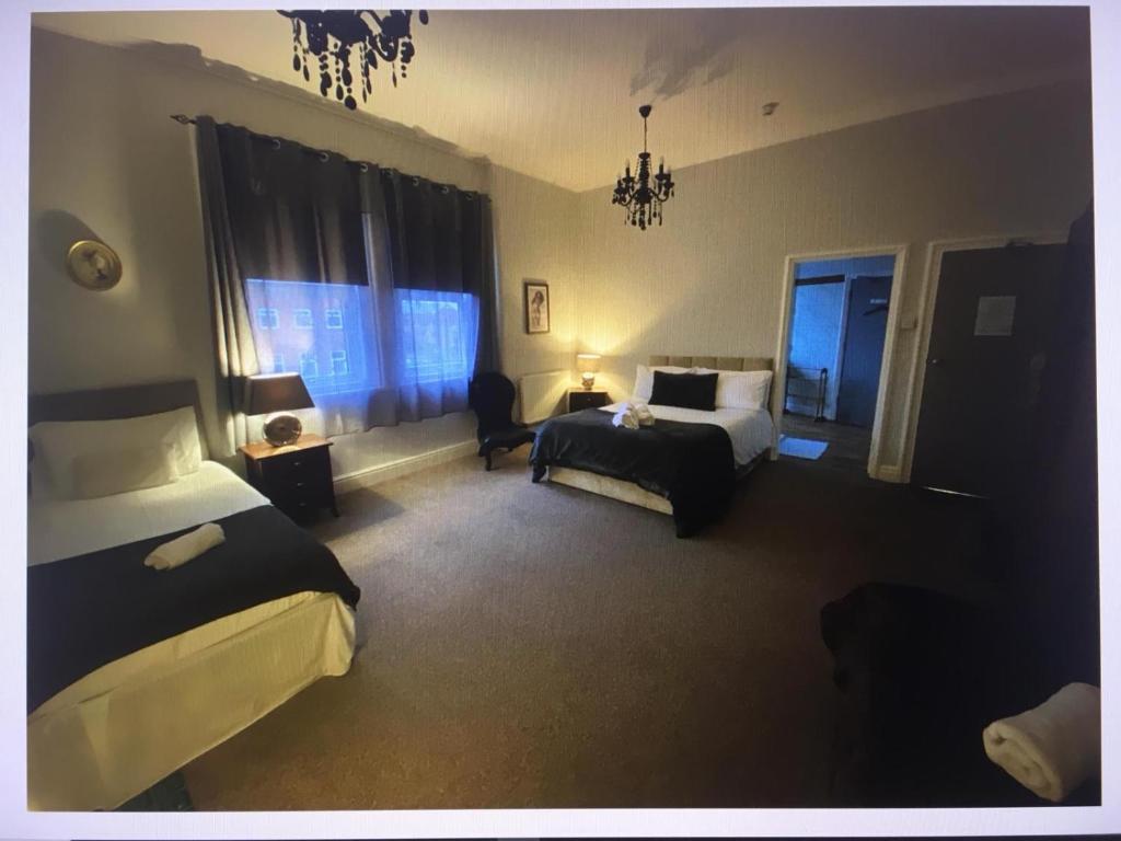 um quarto de hotel com duas camas e uma cama e uma cadeira em St Andrews house Hotel em Preston