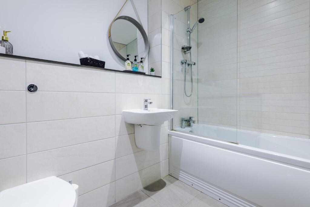 a white bathroom with a sink and a bath tub at Victoria Mill by Staycay in Wigan