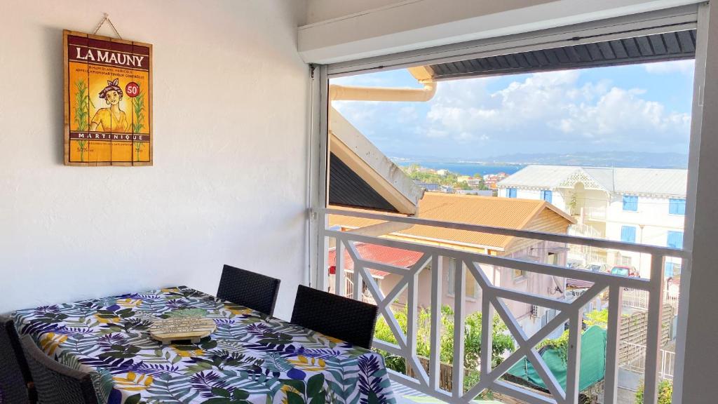 balcón con mesa y vistas a un edificio en Ti Caraïbes, appartement T3 atypique, vue mer, piscine et proche plage, en Les Trois-Îlets