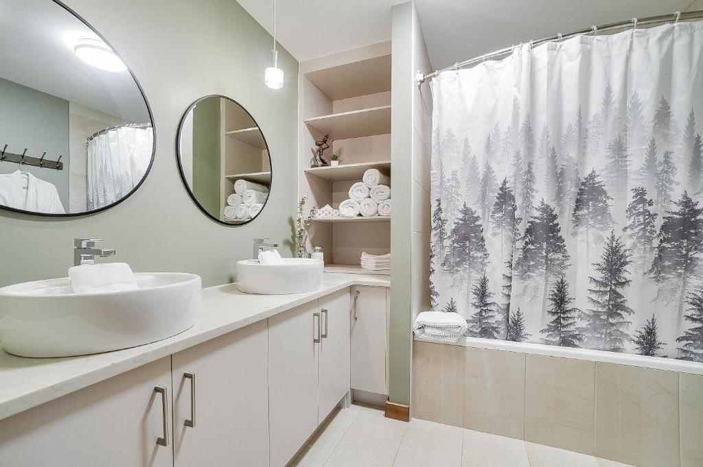 ein Badezimmer mit zwei Waschbecken und einem Duschvorhang mit Wald in der Unterkunft Le Sous Bois 1318 in Saint-Faustin