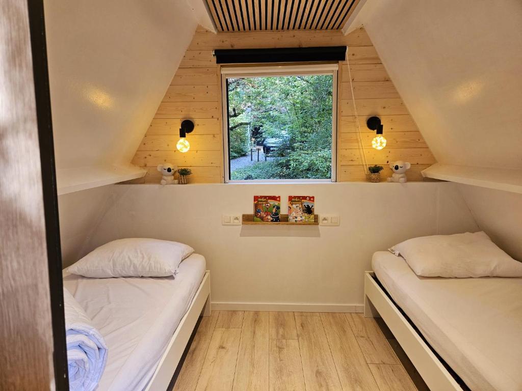 two beds in a small room with a window at de bosdriehoek II in Durbuy