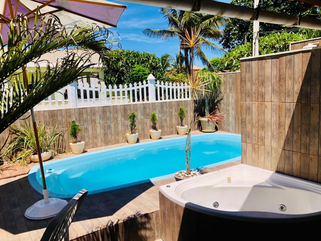 una piscina en el patio trasero de una casa con una valla blanca en Pousada Recanto Beach House - Cabo Frio - Unamar, en Tamoios