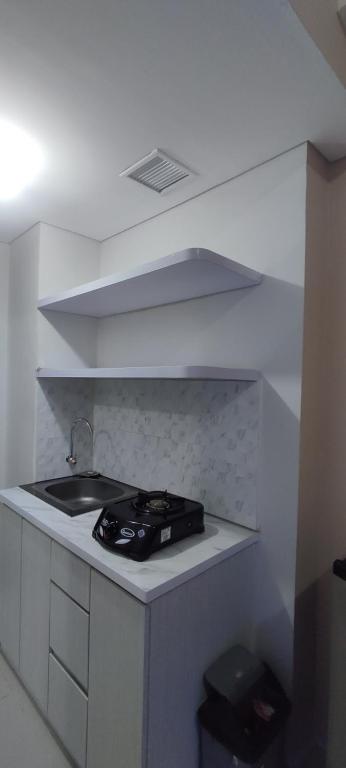 - une cuisine blanche avec évier et cuisinière dans l'établissement Goodroom apartement, à Padurenan
