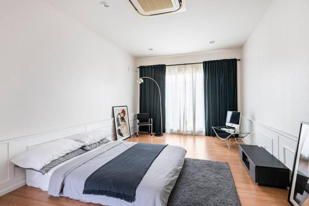 a white bedroom with a large bed and a desk at 55th AREA in Nonthaburi