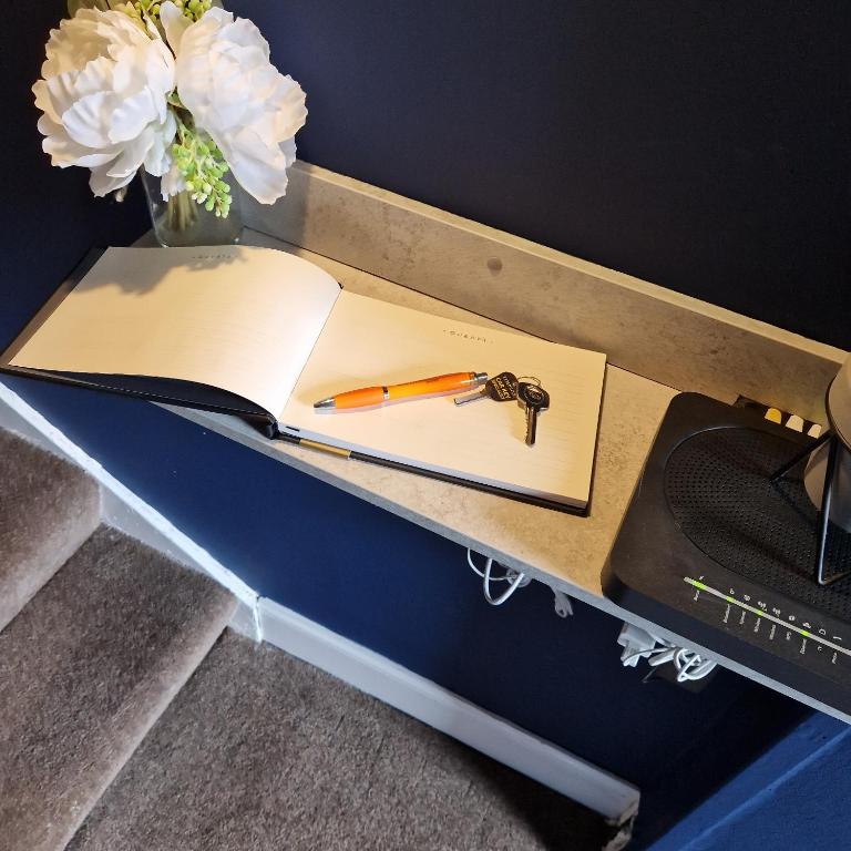 un bolígrafo y un cuaderno en un escritorio junto a un teclado en Hide away (Central Inverurie) en Inverurie
