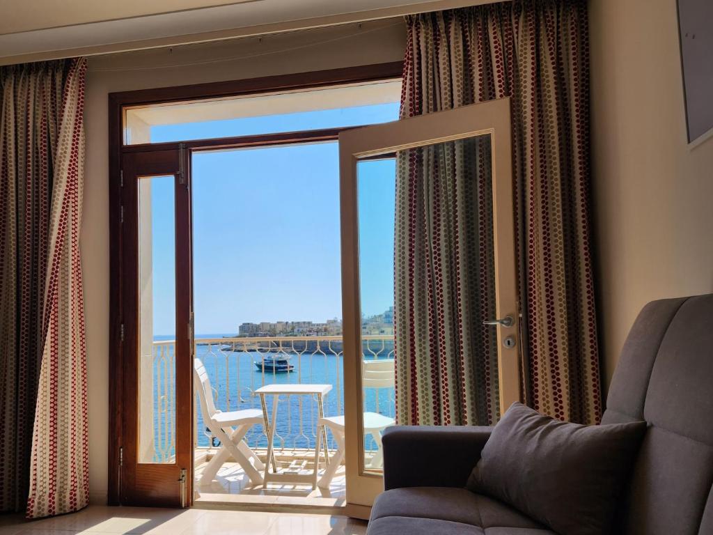 een woonkamer met een glazen schuifdeur met uitzicht bij Seafront Apartment - Wifi - Sleeps 6 - ChrisCourt in Marsaskala