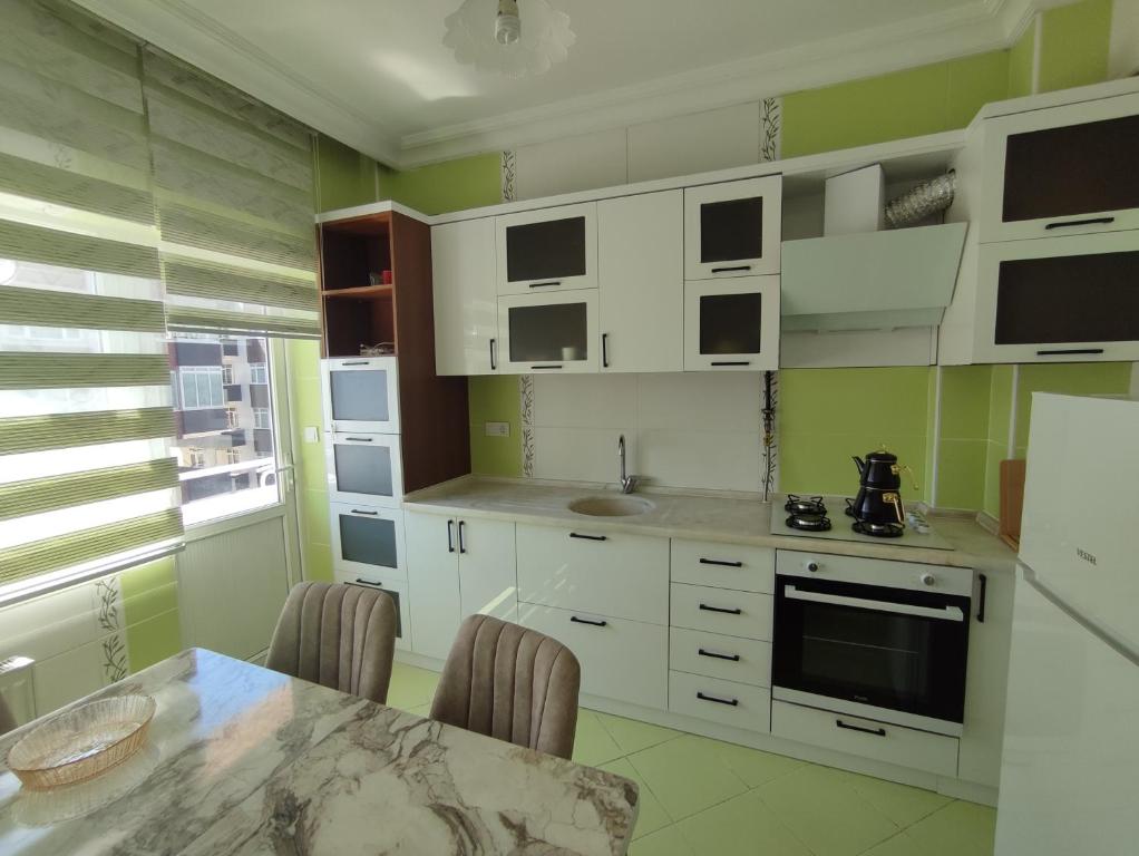 a kitchen with white cabinets and a table with chairs at Large House in Trabzon
