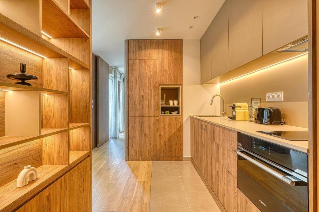 a kitchen with wooden cabinets and a stove at Appartement de luxe - Aux portes de Paris in Saint-Mandé