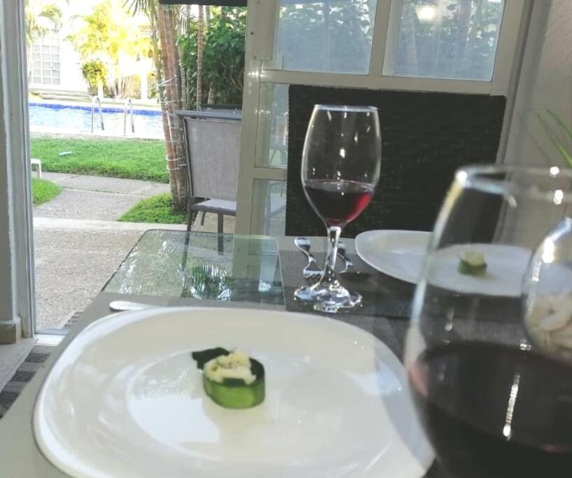 a table with a plate of food and a glass of wine at EXCELENTE Depa en Acapulco Diamante FRENTE AL MAR! in Acapulco