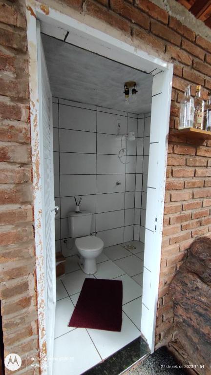 e bagno con servizi igienici in un muro di mattoni. di Rancho de Vidro no Paraíso a Pederneiras