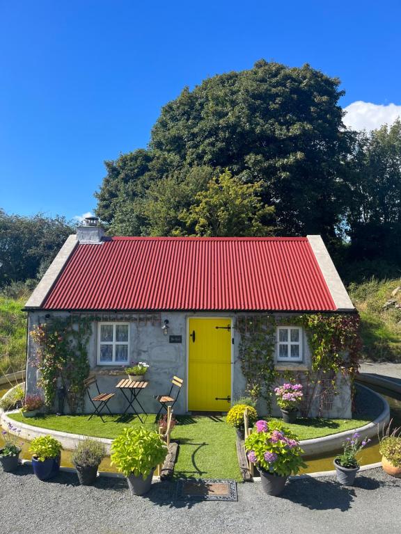 a small house with a red roof and a yellow garage at The Nest Quaint Luxury Cottage Getaway in Tiragarvan