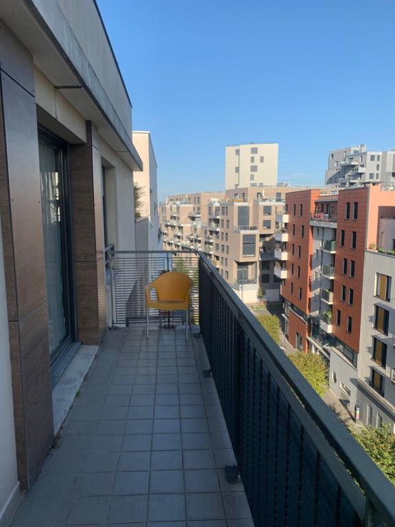 a balcony with a yellow chair on a building at Penthouse avec jacuzzi in Asnières-sur-Seine