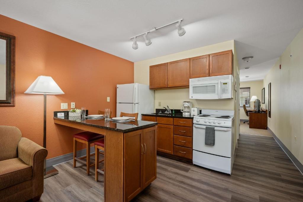 a kitchen with white appliances and wooden cabinets at Affordable Suites of America Stafford Quantico in Stafford