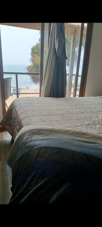 a bedroom with a bed with a view of a beach at Casa playa ConCon in Concón