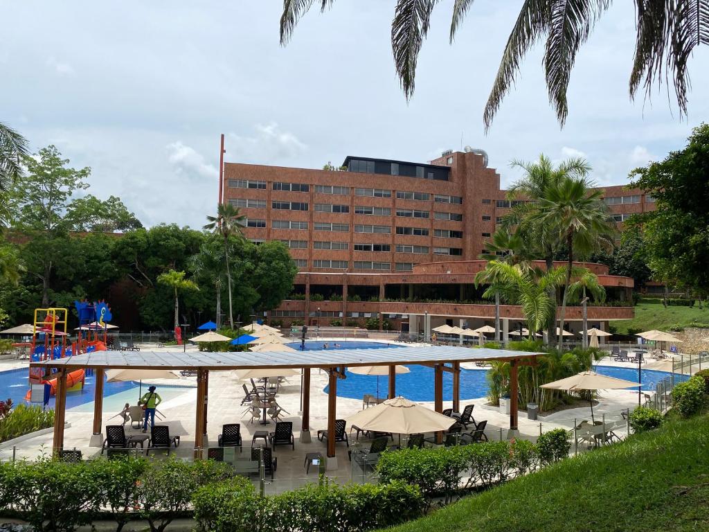 a pool with tables and umbrellas next to a building at Hotel Kualamaná Cafam Melgar in Melgar