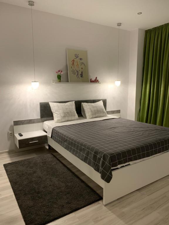 a bedroom with a large bed with a green curtain at Green Divine Apartament in Popeşti-Leordeni