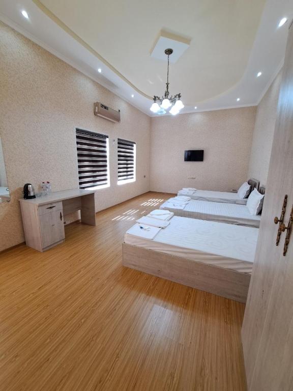 een slaapkamer met 2 bedden en een bureau. bij Tarallo Hotel in Bukhara