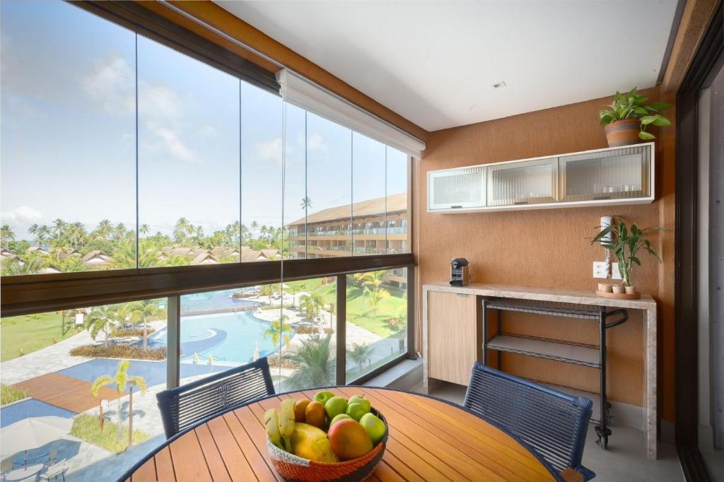 a kitchen with a table with a bowl of fruit at Eco Resort Praia dos Carneiros Apt Luxo Beira Mar in Tamandaré