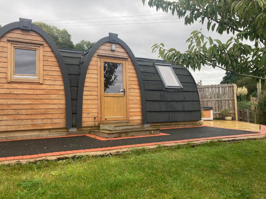 une petite maison avec un toit noir et une porte dans l'établissement Owl Glamping Pod, à Leighton