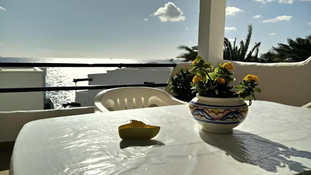 una mesa con un jarrón con flores encima en Apartamento Faro Sardina, en Sardina